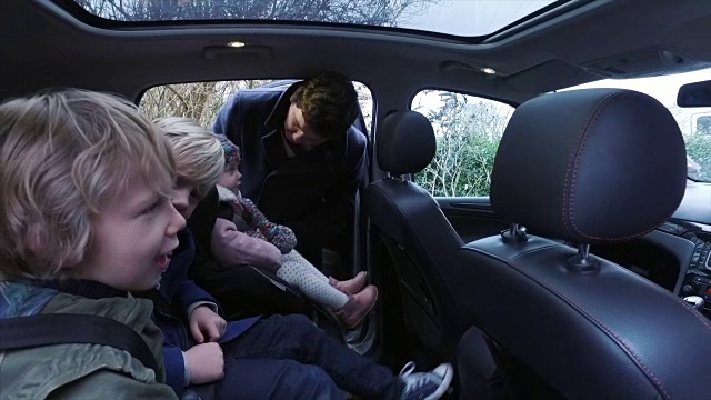 父亲把孩子们放进车里视频素材