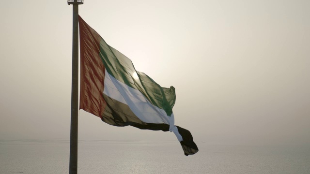 阿拉伯联合酋长国的国旗在风中飘扬。这面国旗悬挂在迪拜联合大厦的旗杆上，这是阿联酋最高的旗杆。视频下载