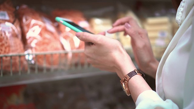 女人在超市使用智能手机，特写视频素材