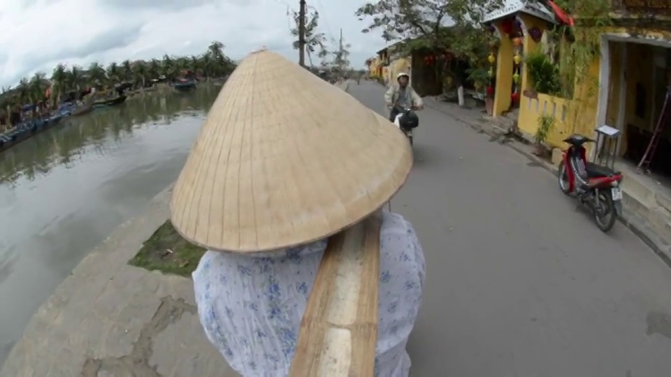 越南会安，一名妇女在街上提着装满水果的篮子视频下载