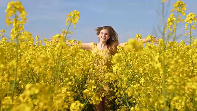 快乐的年轻女子奔跑在盛开的油菜花中视频素材