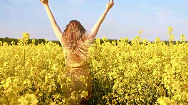 快乐的女人跑过油菜籽田视频素材