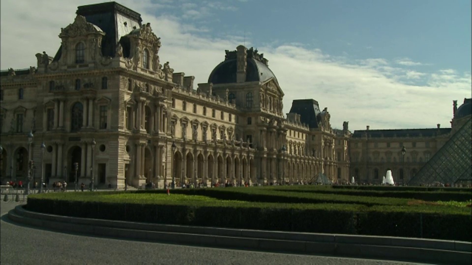 修剪整齐的树篱、喷泉和金字塔装饰着法国巴黎卢浮宫的广场。视频下载