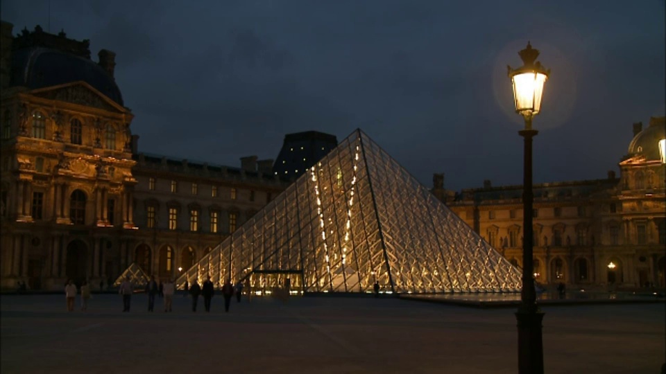 晚上，游客们在法国巴黎的卢浮宫金字塔周围徘徊。视频下载