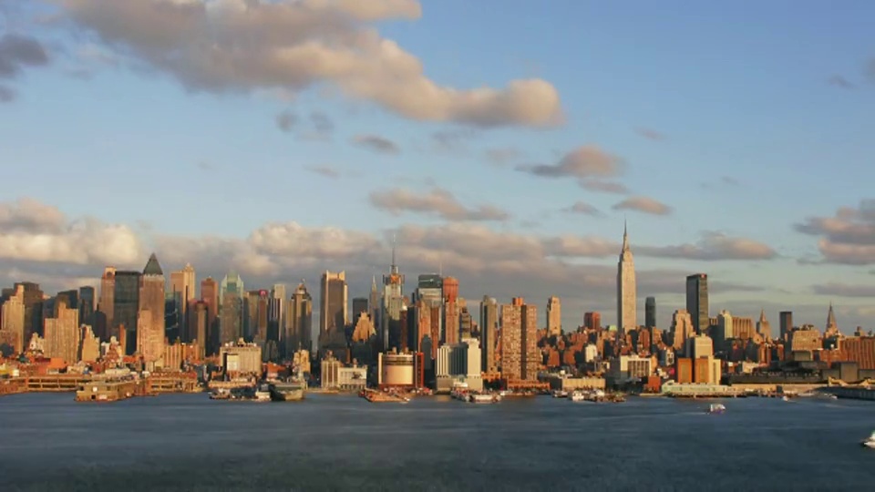 时间流逝广域网拍摄的云在曼哈顿中城天际线日落与船在哈德逊河在前景视频素材