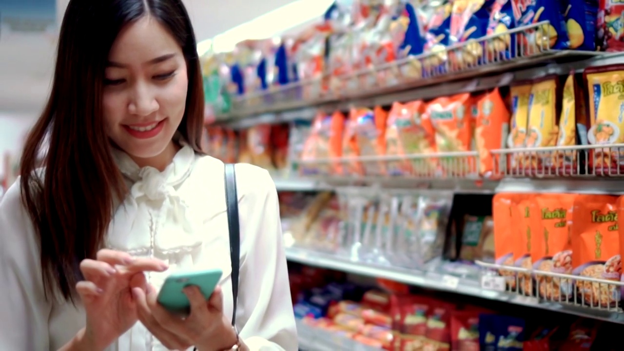 女人在超市用智能手机，慢镜头视频素材