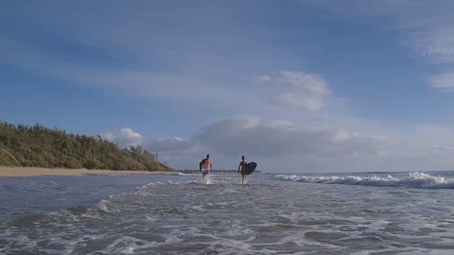 太平洋岛民夫妇慢跑与冲浪板在波浪中视频素材