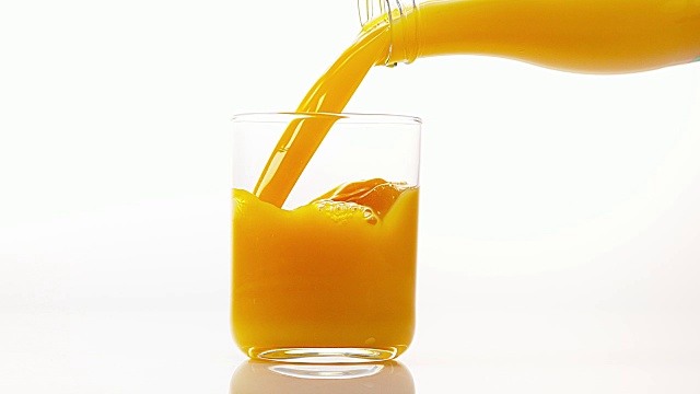在白色背景下，将橙汁倒入玻璃中，慢动作4K视频素材