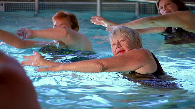 中镜头老年人在游泳池做练习，教练在前面视频下载