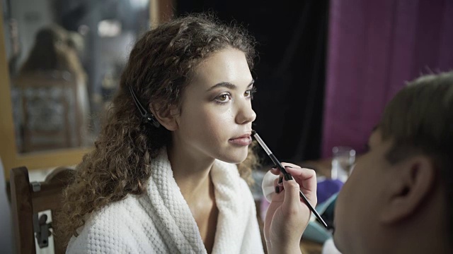 一位化妆师正在用刷子为模特准备嘴唇。视频素材