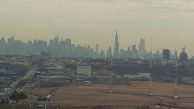 空中升起在黄色田野和工业郊区，远处是纽约的天际线视频素材