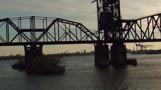 空中摇拍沿着钢或铁桥，远处是费城的天际线视频素材
