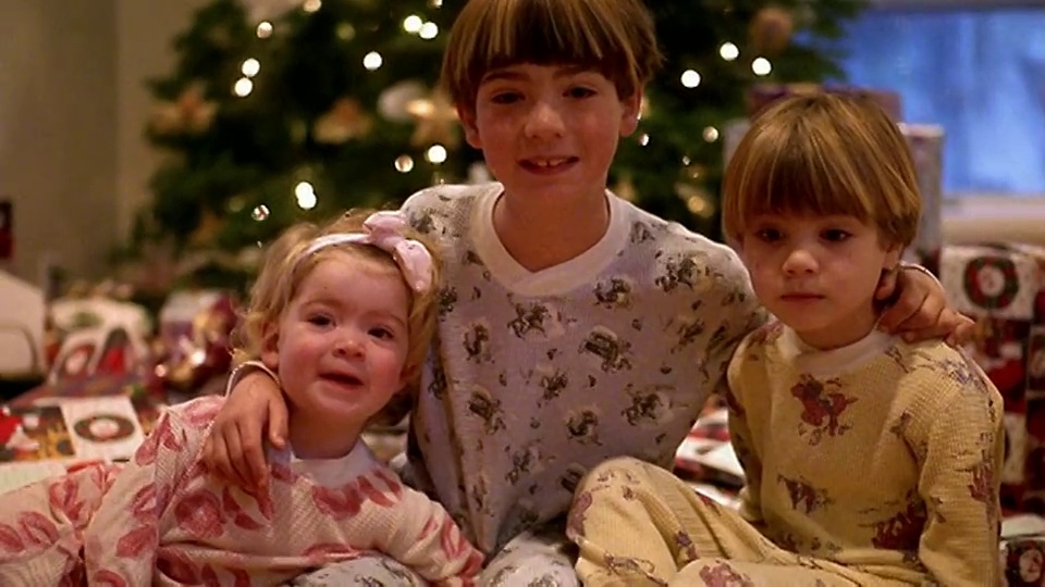 中镜头的小女孩和两个穿着睡衣的男孩在圣诞树前摆姿势视频素材