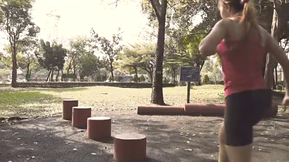 女子在公园的红色方块形状上跳跃的慢动作视频下载