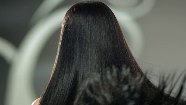 一位美丽的女人在甩动她美丽的长长的黑发。视频下载
