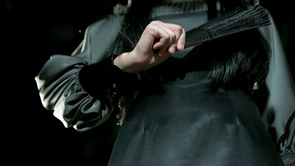 黑衣女子向下挥动黑色折扇。视频下载