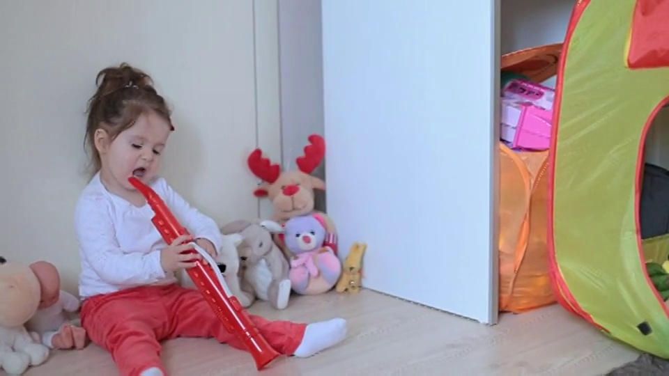 女孩坐在玩具中间，吹长笛视频下载