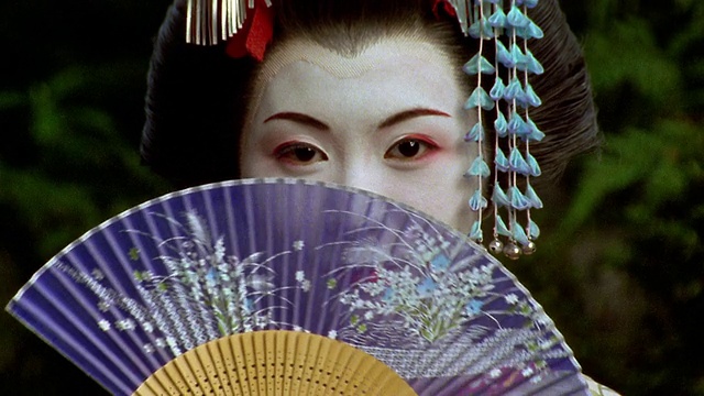 近距离的日本妇女在艺妓化妆和服装移动扇脸部/日本视频下载