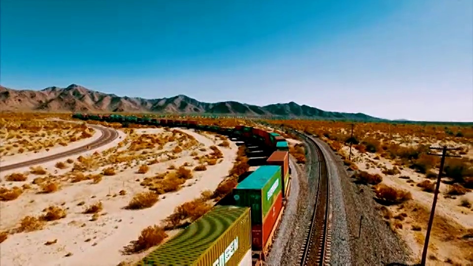 一辆大型集装箱机车沿着美国沙漠的铁轨行驶。视频下载