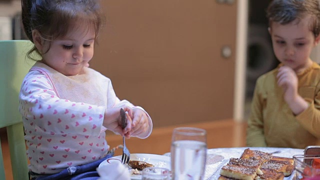 可爱的小女孩在餐桌上用叉子吃饭视频素材