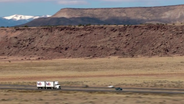 联邦快递半挂车在沙漠公路上行驶。视频素材
