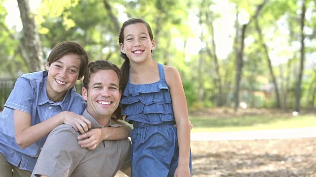 父亲和两个孩子在公园里拥抱视频素材