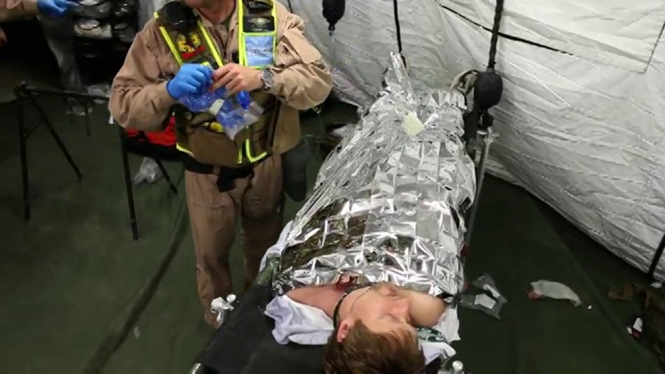 手持广角镜头医疗小组与帐篷里的担架上的伤者交谈和移动——美国海军陆战队成员和纽约消防局成员参加联合演习，旨在加强对巴克莱中心化学和生物袭击的准备视频下载