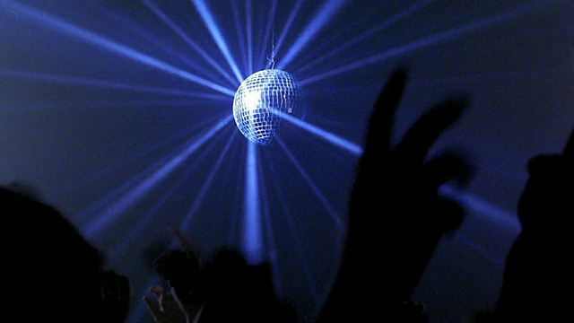 中镜头镜球旋转和反射蓝光与舞者在夜总会举起的手臂视频素材