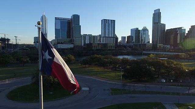 德克萨斯州旗Pan右无人机在日出时靠近旗帜在奥斯汀德克萨斯天际线首都城市景观视频下载
