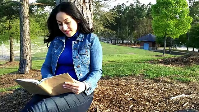 一位拉丁裔女性在公园户外阅读。视频下载