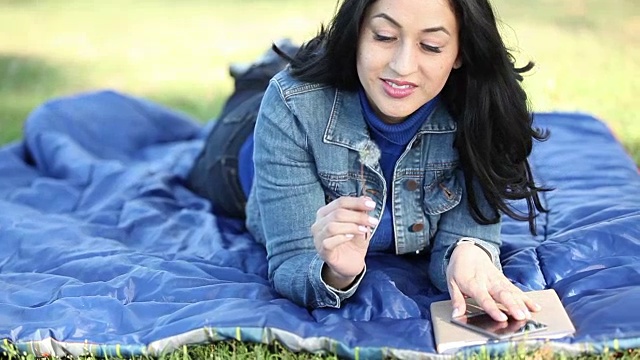 一位拉丁裔妇女在公园户外使用手机。视频下载