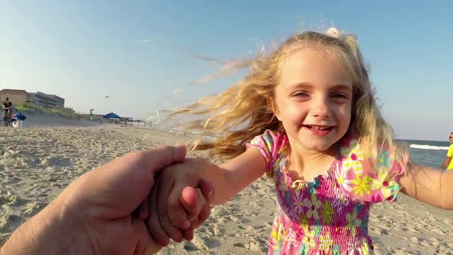 可爱的小女孩和爸爸在阳光明媚的海滩上跳舞视频素材