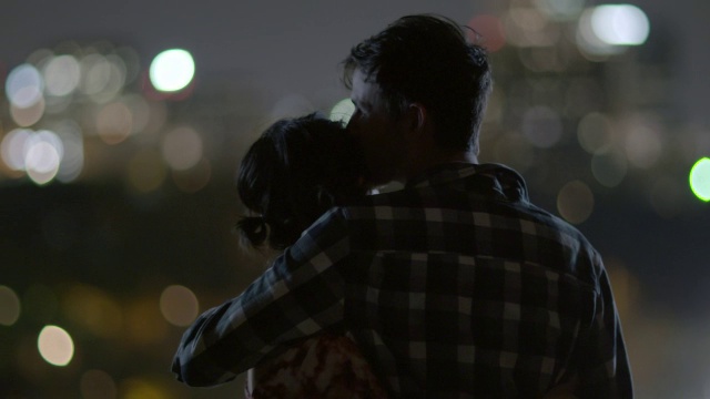 年轻的情侣牵手、拥抱、亲吻，俯瞰城市的天际线视频素材