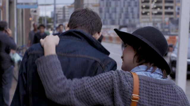 一名年轻女子抚摸着男友的后背，用手臂搂着他穿过奥斯汀市中心视频下载