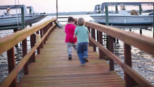 两个男孩跑向一个海洋码头的尽头。视频素材