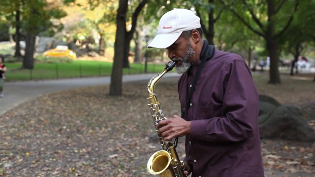 一位街头音乐家在公园里吹萨克斯风。视频下载