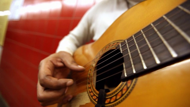 MED黑人弹吉他，而靠在地铁站的红墙锅下的吉他手臂视频素材
