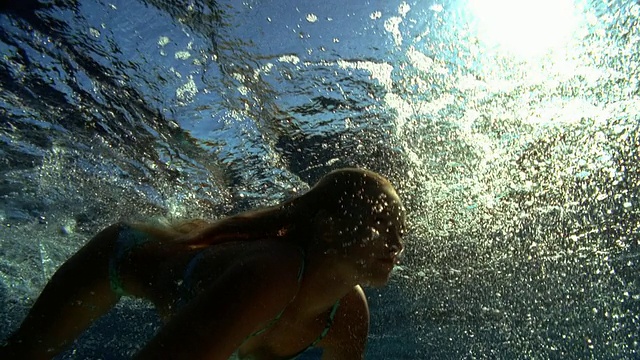 慢动作低角度中镜头女子跳水到水面/塔希提下的冲浪板上视频素材