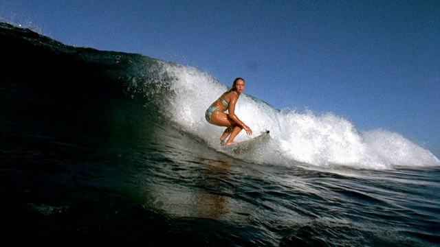 慢镜头泛宽拍摄女性冲浪者骑浪/塔希提视频素材