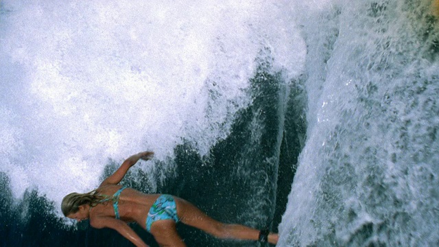 慢动作中镜头跟踪拍摄女性冲浪者骑在浪/大溪地视频素材
