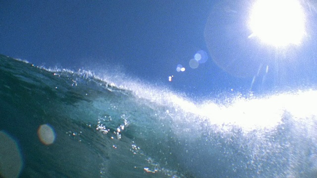慢镜头低角度宽拍摄海浪撞击/太阳在背景/大溪地，法属波利尼西亚视频素材