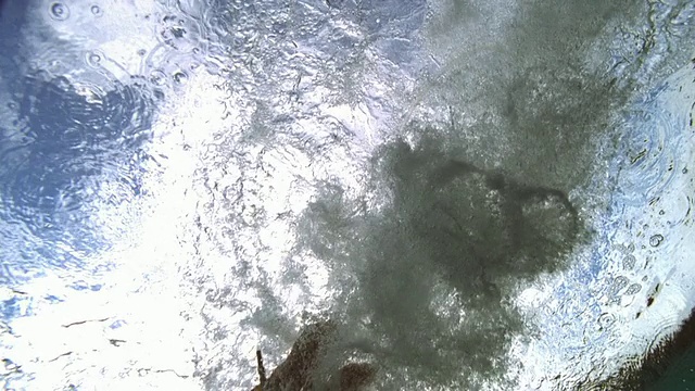 慢动作低角度中拍摄女子跳水在水面上/蓝天和白云的背景视频素材