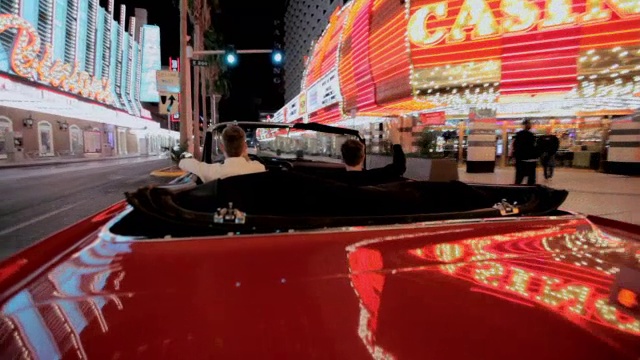 当一名男子驾驶着一辆敞篷车在拉斯维加斯大道上行驶时，车上的灯光会发生反射。视频素材