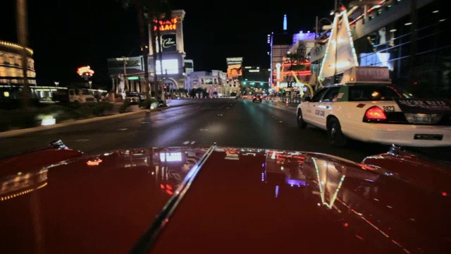 一辆汽车在拉斯维加斯大道上行驶时，会被灯光反射。视频素材