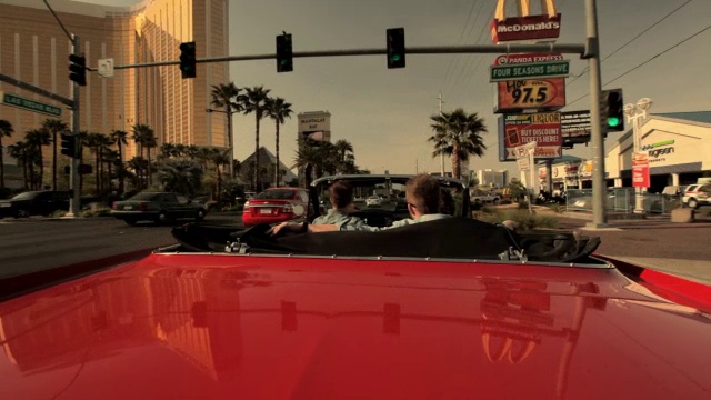 三个男人开着一辆老式的红色敞篷车沿着内华达州拉斯维加斯大道行驶。视频素材