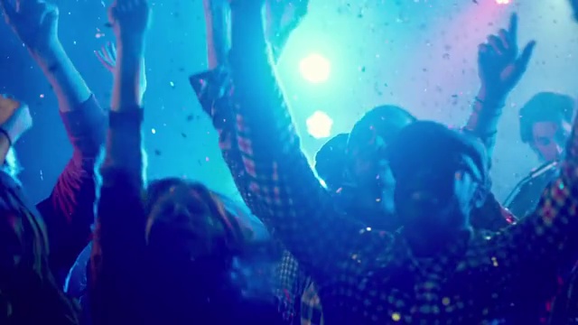 中镜头年轻的成年男女在闪光下跳舞，抬起手(慢动作)视频素材