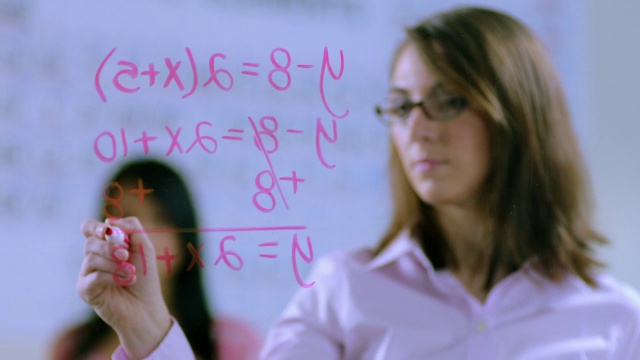 老师在镜头上写方程式，女学生在她身后观察视频下载