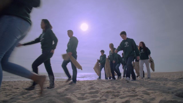 一群志愿者沿着海滩散步。视频素材