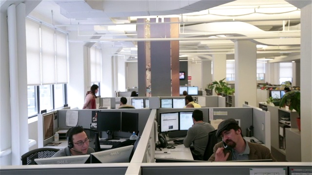 公司人员在办公楼楼层的多个工作站工作(宽，推车拍摄)视频下载