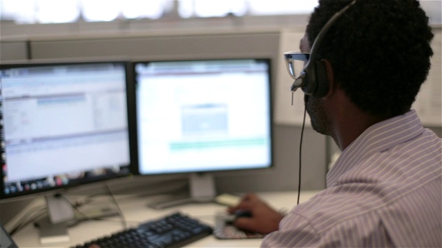 多任务办公人员用耳机说话，用鼠标滚动电脑屏幕视频下载